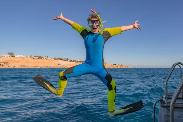 Funny comical snorkeling diver with flippers jump in sea water